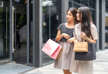 Two asian woman shopping walking together carrying colorful bags and smiling at mall, friendship modern lifestyle, weekend activity and fashion retail marketing, e-commerce deals and discount season