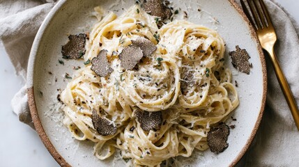 Creamy fettuccine pasta with shaved truffles and grated parmesan on neutral background