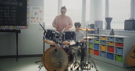 Primary School Boy Practicing Drums in Modern Music Class, Dreaming to Become Drummer. Female Teacher Educating Talented Child to Play Drum Set During Percussion Lesson. Rhythm Education, Musical Art.