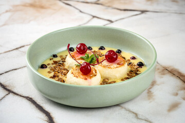 Gourmet syrniki with creamy sauce and fresh berries.