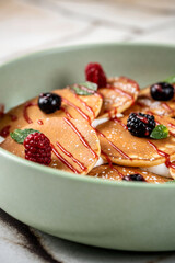 A close-up of delicious mini pancakes with berries.