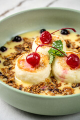 Homemade syrniki with creamy sauce and cherries close-up.