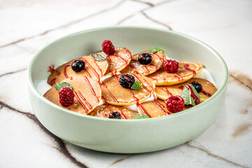 A bowl of mini pancakes with fresh berries.