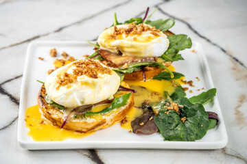 Gourmet Eggs Benedict with a rich hollandaise sauce on a modern plate.