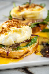 A vertical close-up of gourmet Eggs Benedict with a rich, runny yolk.