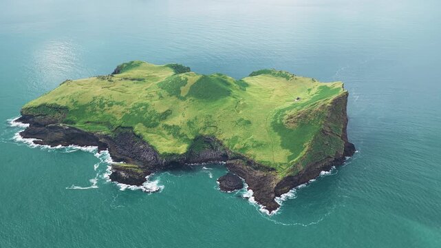 Aerial view of the lush green, isolated Elli&eth;aey island standing boldly against the vast turquoise ocean, creating a striking contrast of colors, Elli&eth;aey, Vestmannaeyjab&aelig;r, Iceland.