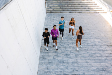 A group of five athletes are running and smiling while one of them turns to them
