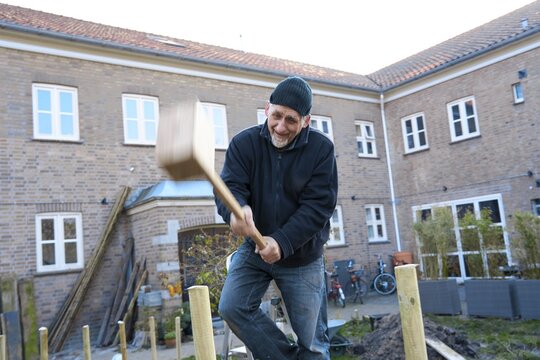 Man building wooden fence outdoors in garden demonstrating independence