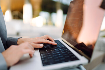 Close-up of a businesswoman typing on a laptop against the backdrop of a modern business center. A...