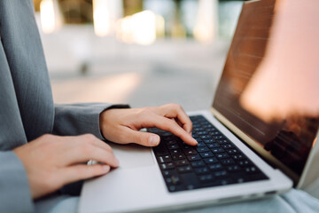 Close-up of a businesswoman typing on a laptop against the backdrop of a modern business center. A...