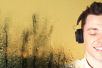 Happy man listening to sounds of nature which making him feel calm. Double exposure with wet window on rainy day