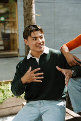 A male student sits on a bench and smiles while talking and gesturing