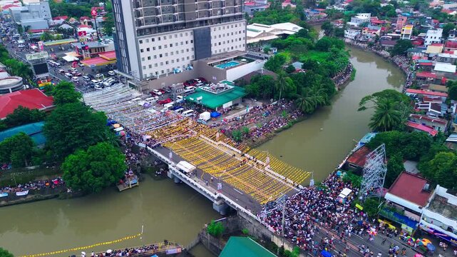 Drone footage of High-rise tower and busy streets during a cultural festival in the Philippines.