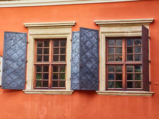Two vintage windows with open metal shutters on a colorful historic building.
