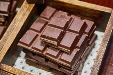Stack of artisanal dark chocolate bars in a rustic wooden box.