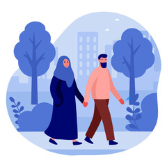 Muslim couple walking hand in hand in urban park with trees  