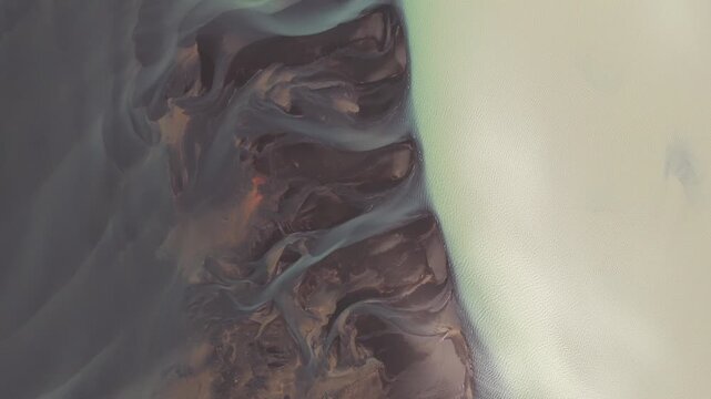 Aerial view of the Hv&iacute;t&aacute; river delta, featuring contrasting dark sediments and light glacial waters, creating a stunning natural landscape, Hv&iacute;t&aacute;, Iceland.