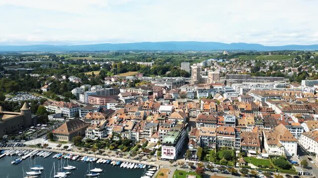 Aerial view of the city with a waterfront area filled with boats, contrasted against the backdrop of buildings with red-tiled roofs, Lake Geneva, Morges, Vaud, Switzerland.