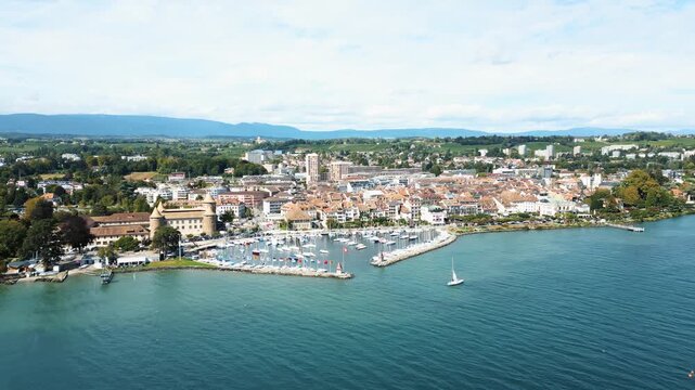 Aerial view of the city with boats in the harbor, contrasted by green trees and the blue water of Lake Geneva, Morges, Vaud, Switzerland.