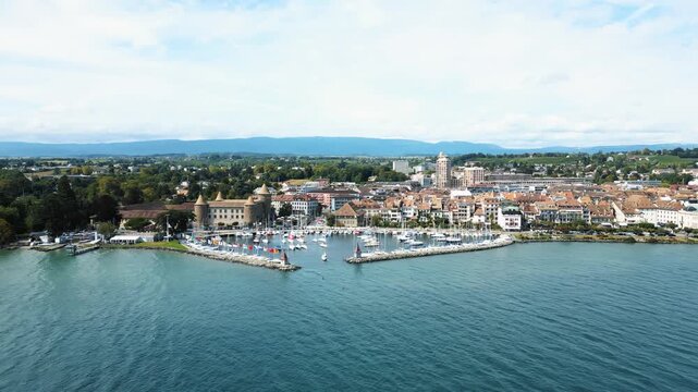 Aerial view of the serene blue waters of Lake Geneva meeting the shore, with the historic Morges Castle standing guard, Lake Geneva, Morges, Vaud, Switzerland.