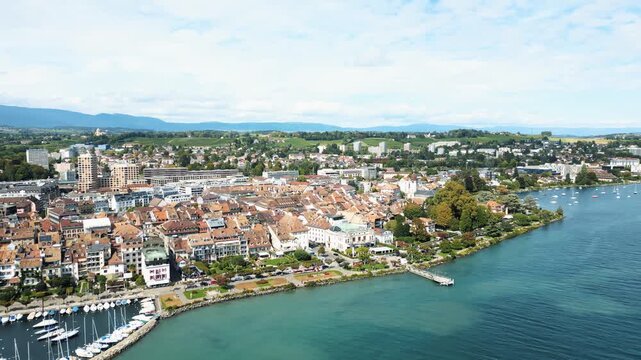 Aerial view of the Lake Geneva waterfront showing the town's architecture meeting the aqua waters, with boats dotted along the coast, Morges, Vaud, Switzerland.