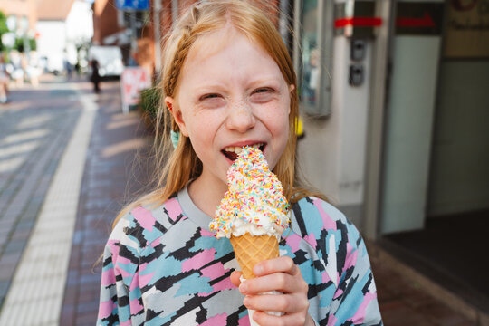 Smiling girl enjoying sprinkled ice cream cone outdoors in summer