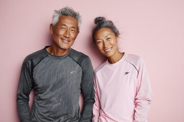 Fototapeta premium Portrait of a blissful asian couple in their 70s wearing a moisture-wicking running shirt in pastel or soft colors background