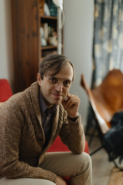 Psychotherapist sitting indoors in casual sweater with glasses