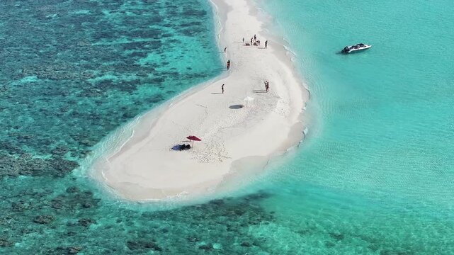 Aerial view of a pristine white sandbank contrasting against the turquoise waters, with people enjoying the tropical scenery, Thoddoo, Alif Alif Atoll, Maldives.