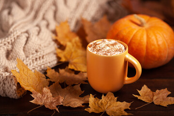 Pumpkin spice latte with autumn leaves and cozy knitted sweater
