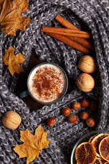 Autumn latte still life, knitted scarf, nuts and leaves