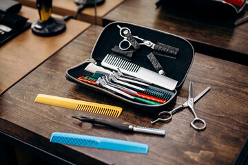 Hair scissors and colorful combs on wooden table in professional salon.