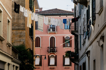 Picturesque Venice architecture with pastel pink walls, wooden balconies, and laundry drying in the sun, offering a glimpse into the authentic lifestyle of local Venetian neighborhoods