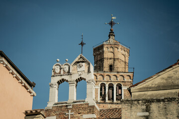 Historic Venetian church with bell gable and brick tower topped with cross against clear sky, showcasing Italian religious architecture, cultural heritage and spiritual city landmark