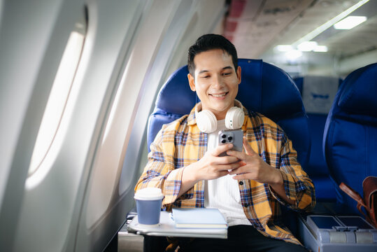Relaxed young traveler enjoying music with headphones and smartphone during a flight. Perfect for lifestyle, leisure, and digital nomad travel concepts.