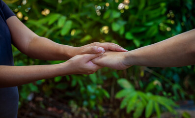 Woman hand as lending a helping hand as trust together with compassion concept as lens flare scene at park