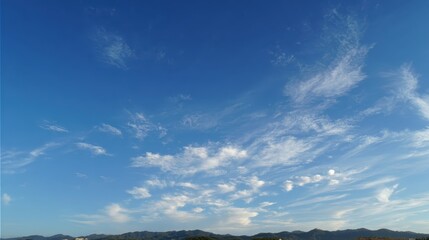 Fototapeta premium Azure Canvas: A bright blue sky adorned with delicate, wispy clouds. Capturing the essence of the expansive atmosphere