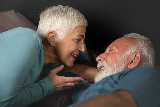 Portrait of happy senior couple smiling each other on bed