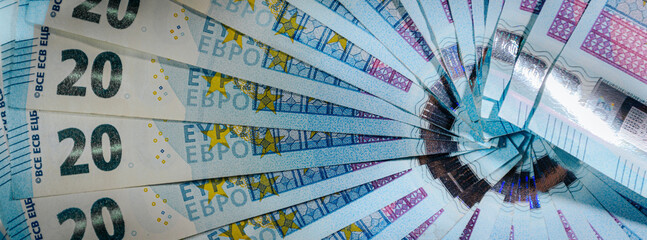 Fan arrangement of 20 euro banknotes spread on a white background, symbolizing cash, savings, and...