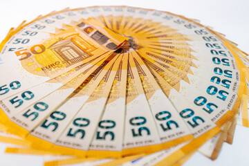 Circular arrangement of 50 euro banknotes fanned out in a complete ring on a white background, symbolizing wealth, finance, and economic prosperity.