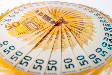 Circular arrangement of 50 euro banknotes fanned out in a complete ring on a white background,...