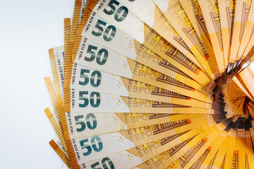 Circular arrangement of 50 euro banknotes fanned out in a complete ring on a white background,...