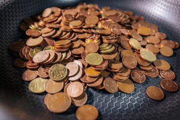 A frying pan filled with euro cent coins, symbolizing money, savings, financial struggles, or the concept of cooking up wealth and economic value.