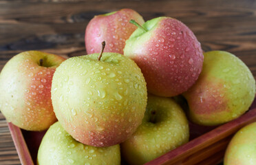 Apples in a wooden crate on a wooden background. Close-up. Apples with water droplets.