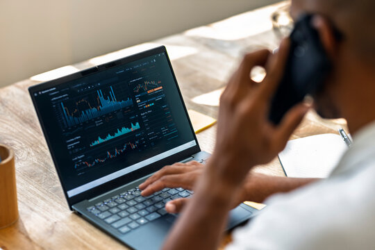 Trader working on financial analysis at home office with laptop