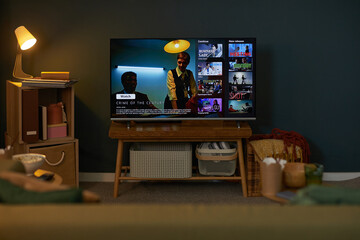 Living room scene showing television on wooden stand displaying streaming service interface with...