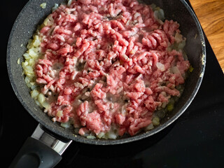 Frying bolognese sauce - minced pork meat with onion in frying pan