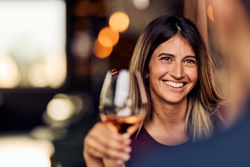 Smiling Woman Enjoying a Glass of Wine at a Cozy Night Out