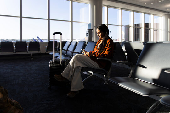 Businesswoman using smartphone while waiting in airport terminal