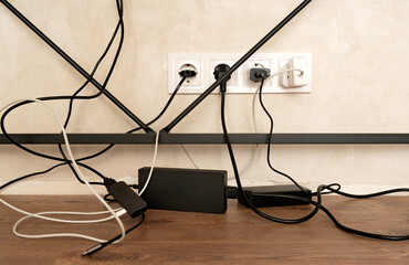 Workplace organization. Messy cables and wires under desk in home office interior, symbolizing electricity connection, technology and disorganized workspace.